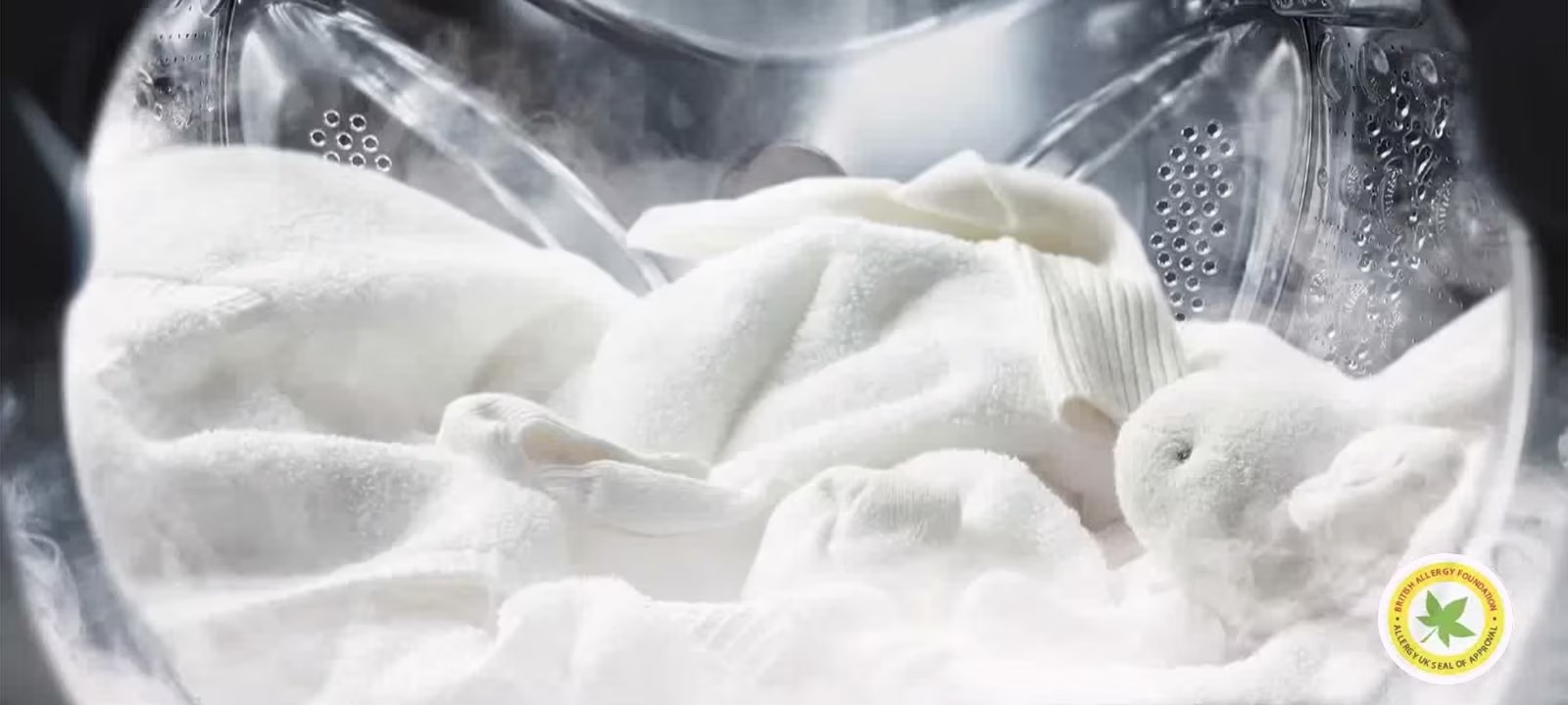 Máy giặt đang giặt khăn và quần áo trắng, kèm nhãn chứng nhận Allergy UK